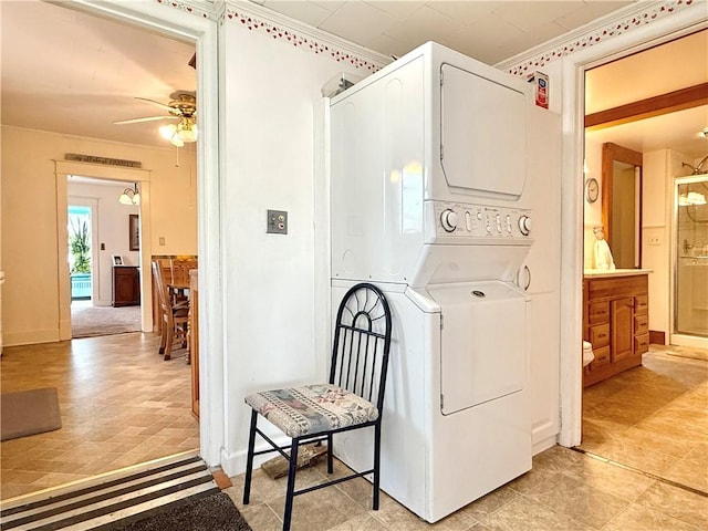 laundry room featuring stacked washing maching and dryer, ceiling fan, and laundry area