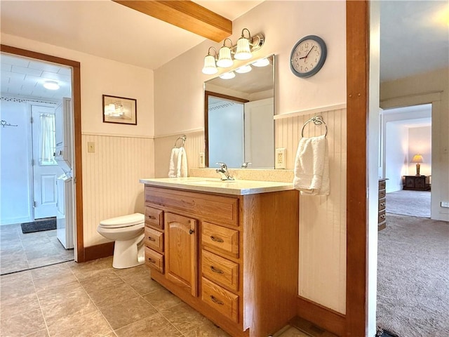 bathroom with washer / dryer, a wainscoted wall, vanity, and toilet
