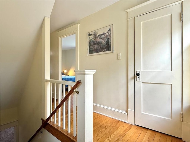 interior space featuring baseboards, an upstairs landing, and light wood-type flooring