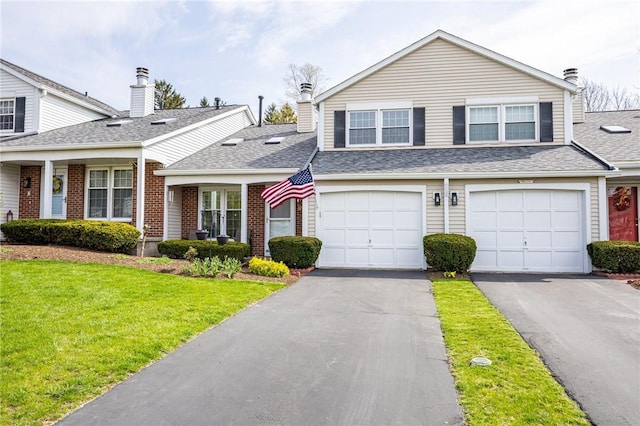 view of front of house with a shingled roof, aphalt driveway, brick siding, and a front yard