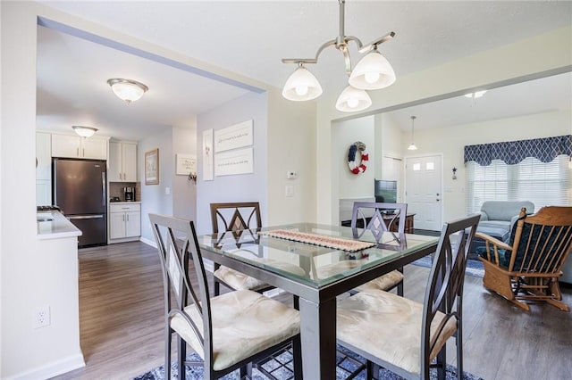 dining area featuring baseboards, a notable chandelier, and dark wood-style floors