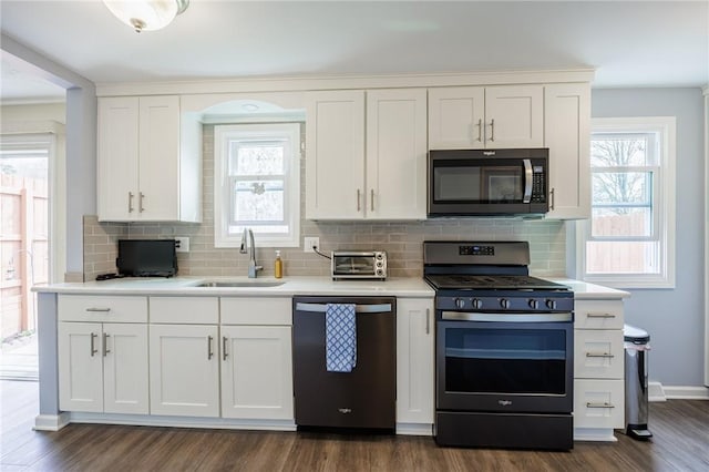 kitchen with decorative backsplash, light countertops, a sink, dark wood finished floors, and appliances with stainless steel finishes