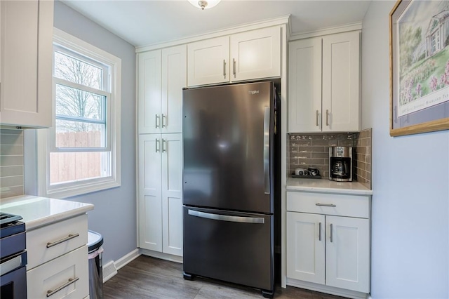 kitchen with light countertops, white cabinets, freestanding refrigerator, and backsplash