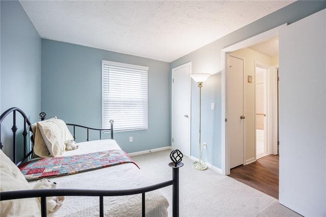 bedroom featuring a textured ceiling, baseboards, and carpet