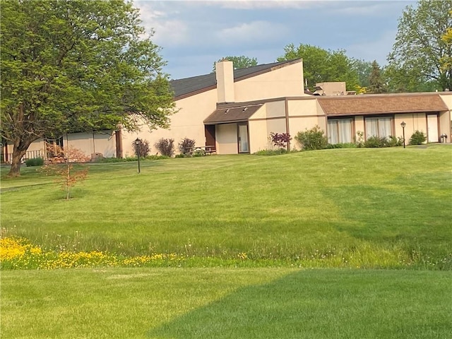 rear view of house with stucco siding and a yard