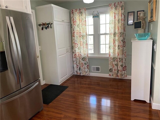 unfurnished dining area featuring baseboards, visible vents, and dark wood finished floors
