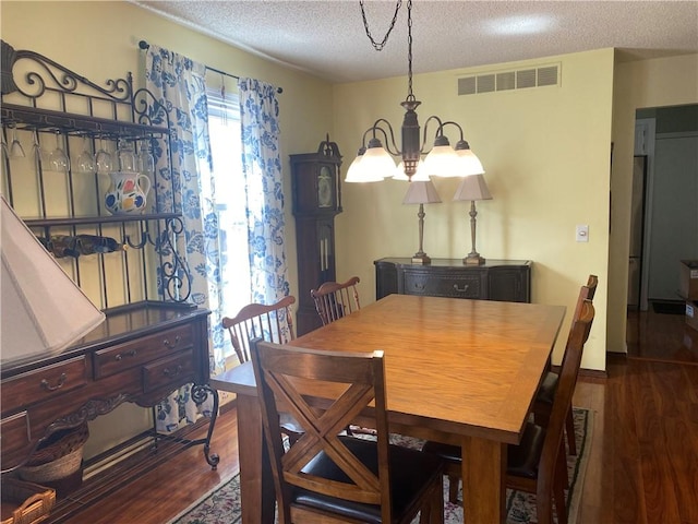dining room with an inviting chandelier, wood finished floors, a textured ceiling, and visible vents