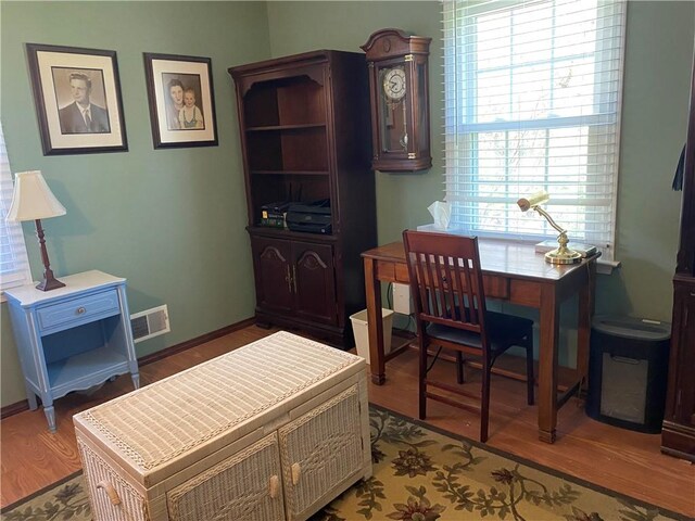 office area with visible vents, baseboards, wood finished floors, and a healthy amount of sunlight