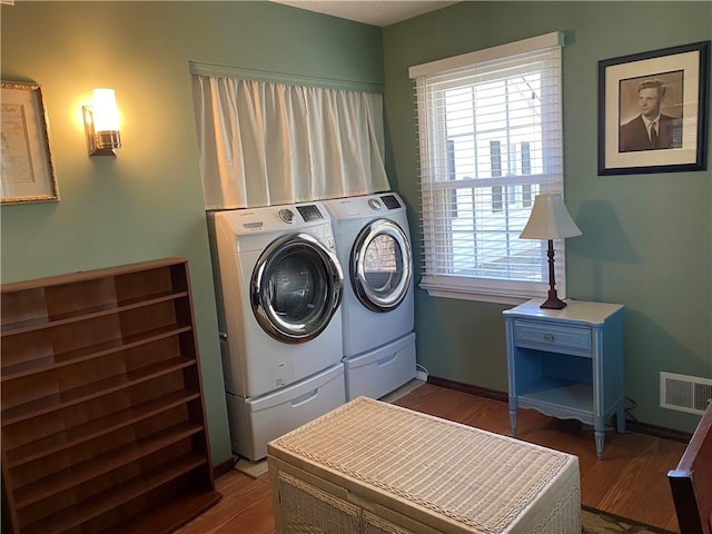 laundry room with dark wood-style flooring, visible vents, washing machine and dryer, and plenty of natural light