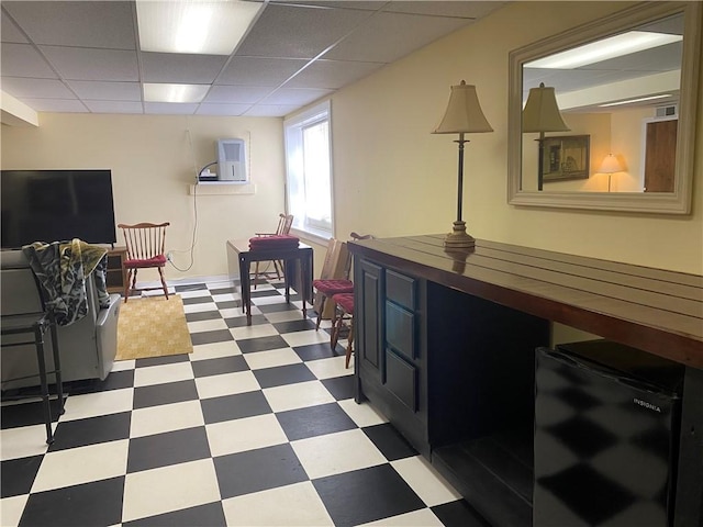 living area featuring tile patterned floors and a drop ceiling