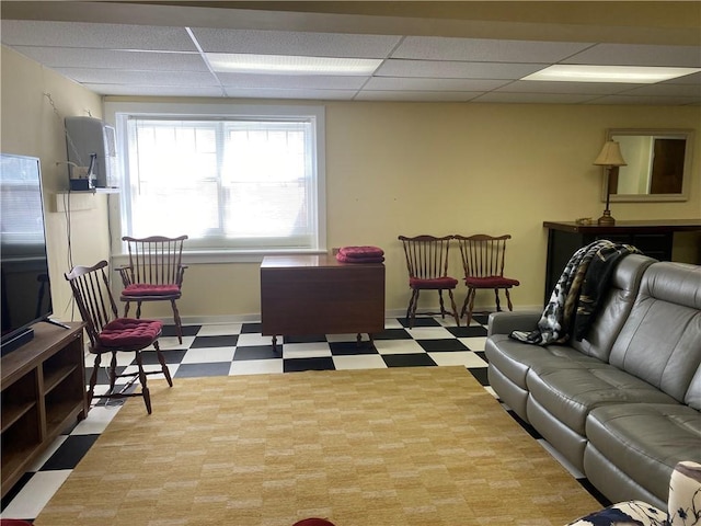 living room with tile patterned floors, baseboards, and a paneled ceiling