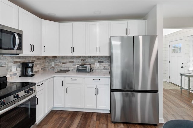 kitchen featuring light countertops, appliances with stainless steel finishes, dark wood-style floors, and tasteful backsplash