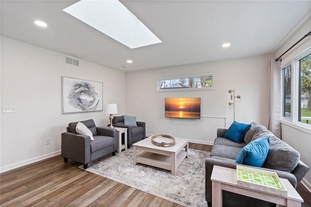living area featuring a skylight, recessed lighting, wood finished floors, and visible vents