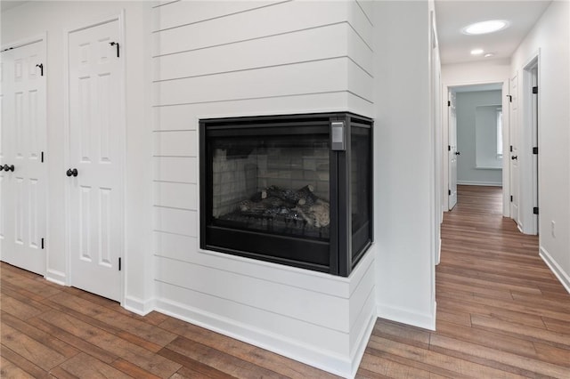 room details with a multi sided fireplace, recessed lighting, baseboards, and wood finished floors