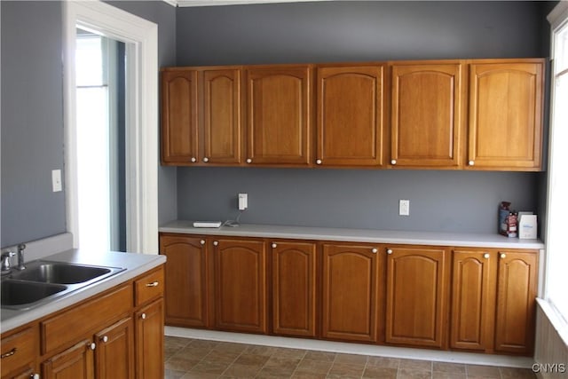 kitchen with brown cabinetry, a sink, and a wealth of natural light