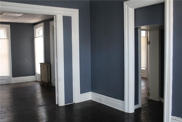 spare room with baseboards and dark wood-type flooring