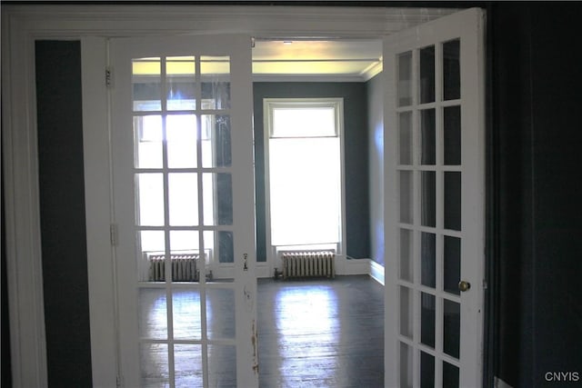 doorway with crown molding, radiator, french doors, and wood finished floors