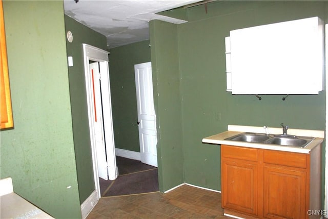 kitchen featuring baseboards, a sink, and light countertops