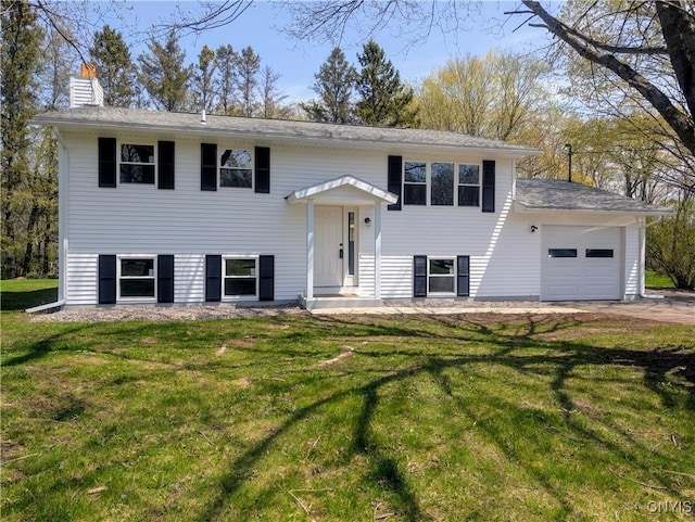 raised ranch with a garage, a chimney, and a front yard