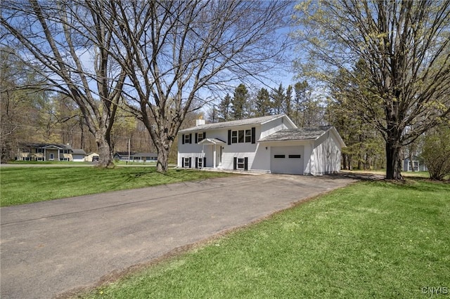 view of front of home featuring an attached garage, driveway, a chimney, and a front yard