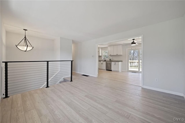 spare room with baseboards, visible vents, ceiling fan, and light wood finished floors