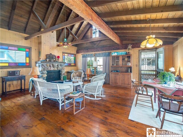 dining space with wood walls, a fireplace, hardwood / wood-style floors, vaulted ceiling with beams, and wood ceiling