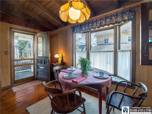 dining space featuring wood walls, wooden ceiling, wood finished floors, and a healthy amount of sunlight