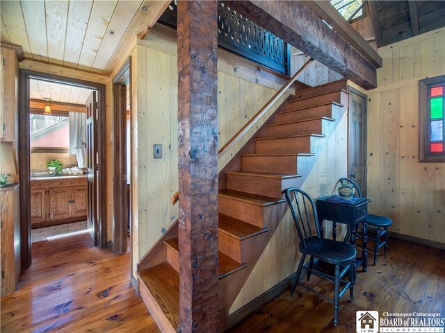stairs featuring wooden walls, wood ceiling, and hardwood / wood-style floors