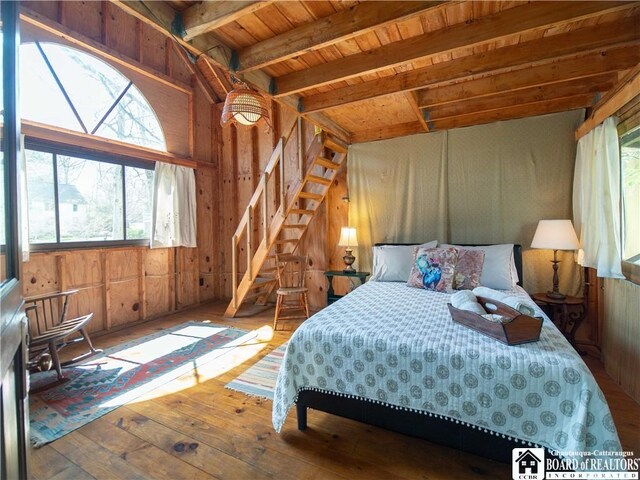 bedroom with wood-type flooring, wooden walls, wooden ceiling, and beamed ceiling