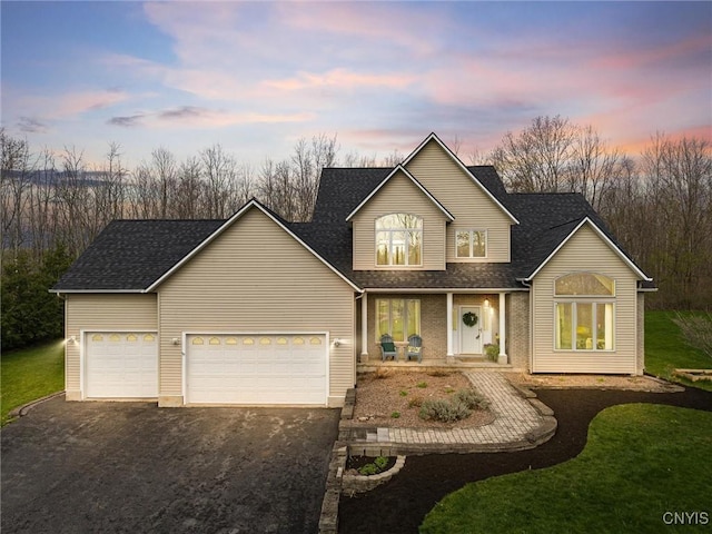 traditional-style home with an attached garage, aphalt driveway, a front yard, roof with shingles, and a porch