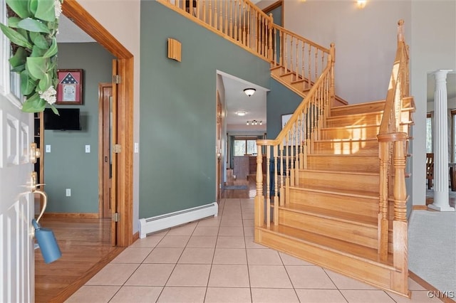 staircase with baseboards, a baseboard radiator, a high ceiling, and tile patterned flooring