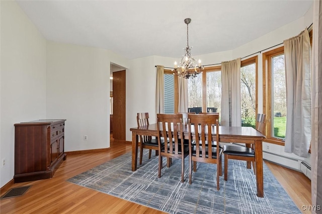dining room with a chandelier, baseboards, wood finished floors, a baseboard radiator, and visible vents