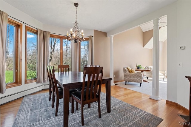 dining room with baseboards, ornate columns, wood finished floors, and a chandelier