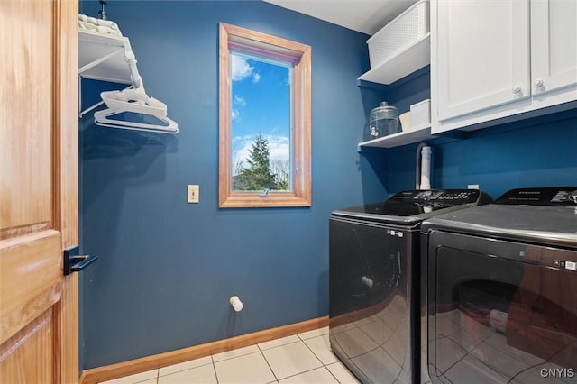 clothes washing area with baseboards, light tile patterned flooring, cabinet space, and washer and clothes dryer