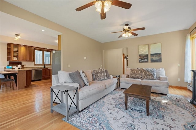 living area with baseboards, ceiling fan, a baseboard heating unit, and light wood-style flooring