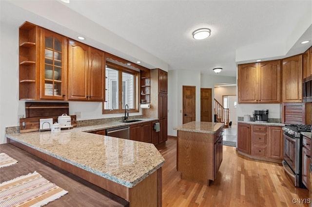 kitchen with open shelves, a kitchen island, light wood-style floors, light stone counters, and stainless steel appliances