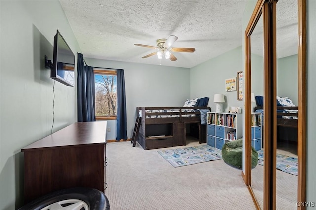 carpeted bedroom featuring a ceiling fan and a textured ceiling