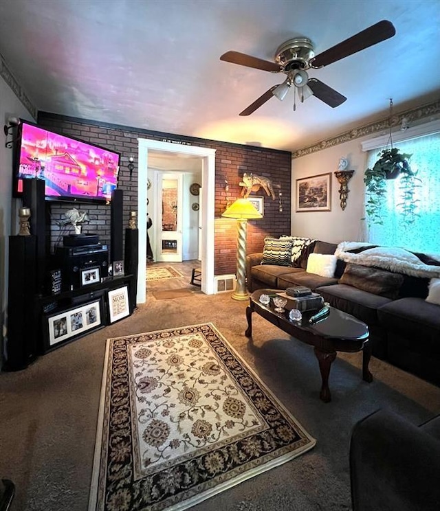 carpeted living room with a ceiling fan and brick wall