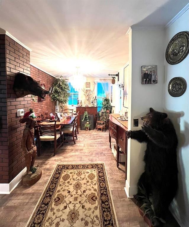 corridor featuring crown molding, baseboards, an inviting chandelier, and wood finished floors