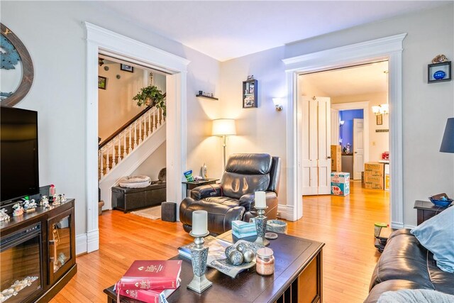 living room featuring stairway, baseboards, and light wood finished floors