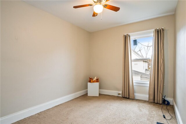 empty room featuring a ceiling fan, baseboards, and light carpet