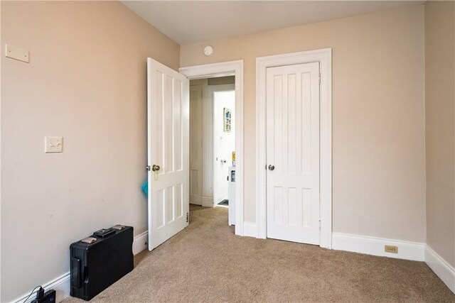 bedroom with baseboards, light carpet, and a closet
