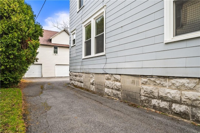 view of property exterior featuring a garage and aphalt driveway