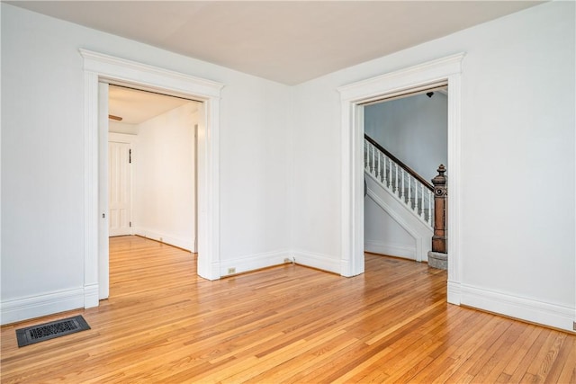 spare room with stairway, visible vents, baseboards, and light wood finished floors