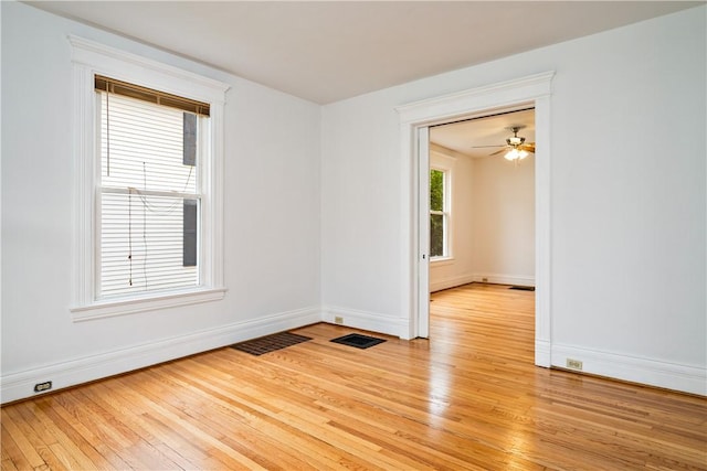 spare room with visible vents, a ceiling fan, light wood finished floors, and baseboards