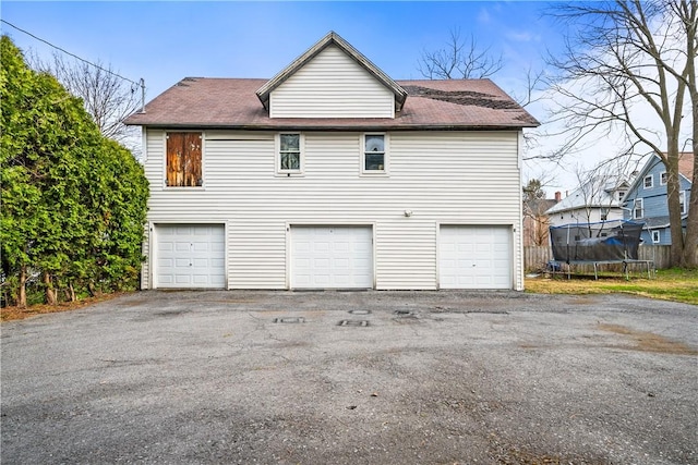 garage featuring a trampoline and aphalt driveway