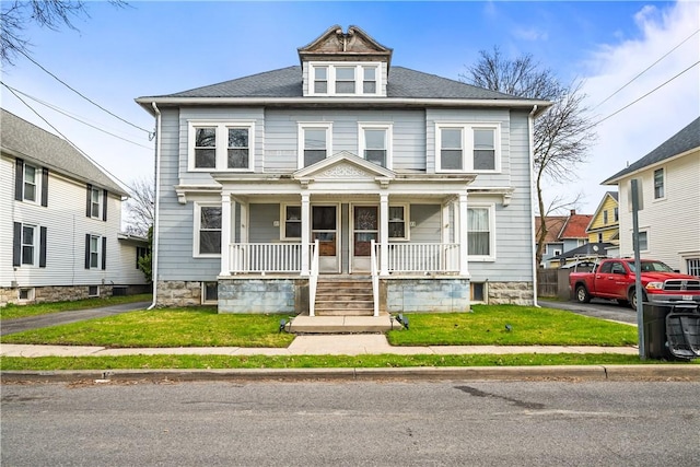 american foursquare style home with a porch and a front lawn