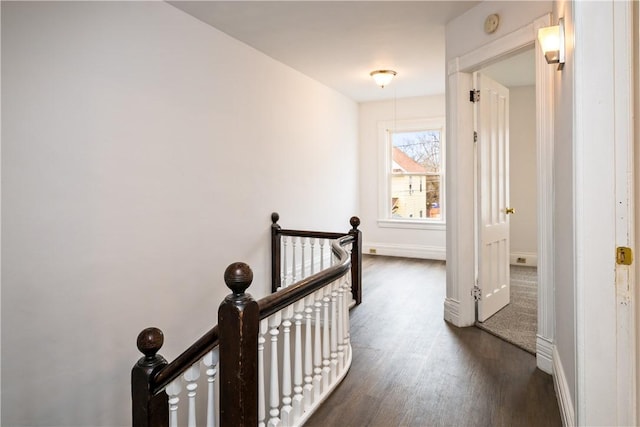 hallway with baseboards, dark wood-style floors, and an upstairs landing