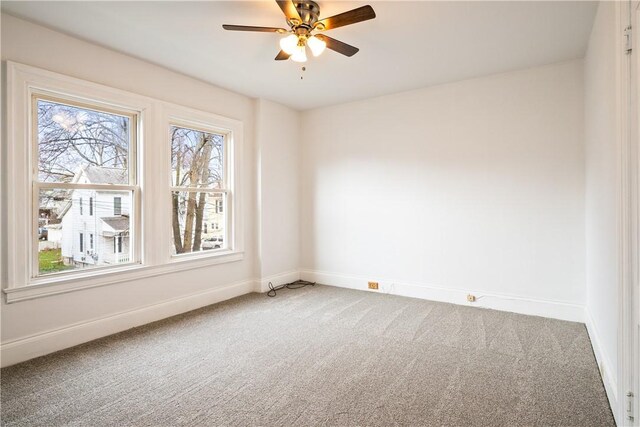 carpeted spare room featuring baseboards, a ceiling fan, and a wealth of natural light