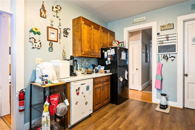 kitchen featuring freestanding refrigerator, wood finished floors, refrigerator, light countertops, and brown cabinets